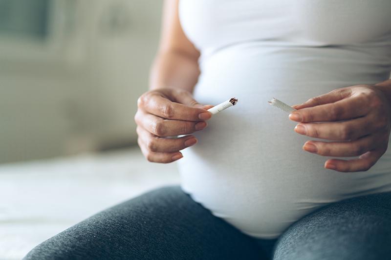 Eine Schwangere Frau zerbricht eine Zigarette